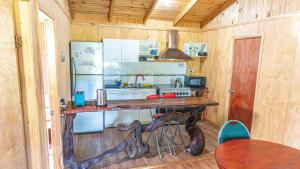 uma cozinha com uma mesa, um frigorífico e um fogão em Cabañas Estrella del Sur em Puerto Varas