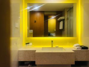 La salle de bains est pourvue d'un lavabo et d'un grand miroir. dans l'établissement Holiday Inn Amritsar Ranjit Avenue, an IHG Hotel, à Amritsar