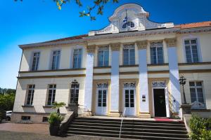 een groot wit gebouw met een trap ervoor bij Schlosshotel Westerholt in Herten