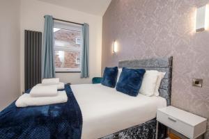 a bedroom with a large white bed with blue pillows at The Retreat At The Lawrence Apartments in York