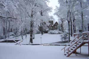 un cortile coperto da neve con una casa e alberi di Paihuen - Resort De Montaña a San Martín de los Andes