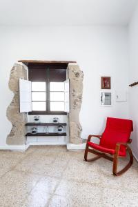 a red chair in a white room with a window at El Hostal del Cubo in San Juan de la Rambla