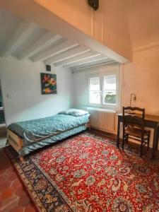 a bedroom with a bed and a table and a red rug at Le val en chêne in Choisy-au-Bac