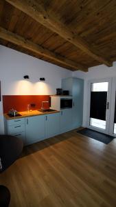 a kitchen with white cabinets and a wooden floor at Remise Brasch - Zwischen Bahnhof und Elbe in Wittenberge