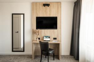 a desk with a chair and a television on a wall at City hotel Terneuzen in Terneuzen