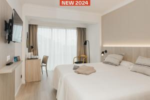 sypialnia z białym łóżkiem i telewizorem w obiekcie Minura Cala Galdana & Apartamentos d'Aljandar w Cala Galdana