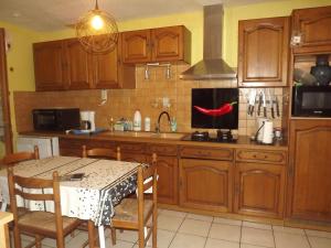 - une cuisine avec des placards en bois, une table et un évier dans l'établissement Bienvenue à La Noyeraie, à Bio