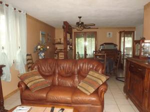 - un canapé en cuir brun dans un salon avec une table dans l'établissement Bienvenue à La Noyeraie, à Bio