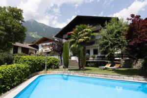 a villa with a swimming pool in front of a house at Garni Juval in Tirolo