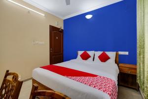 - une chambre dotée d'un mur bleu et d'un lit avec des oreillers rouges dans l'établissement OYO Kakkanad Heights Inn, à Kakkanad
