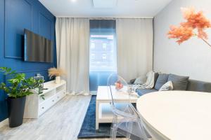 een woonkamer met blauwe muren en een witte tafel bij Apartament BIANCO w sercu Śląska in Ruda Śląska