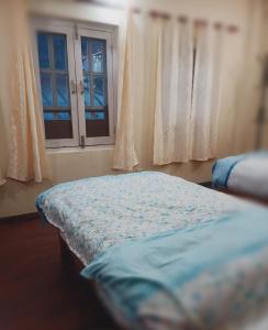 Schlafzimmer mit einem Bett und einem Fenster in der Unterkunft Nirvana Kuti in Kathmandu