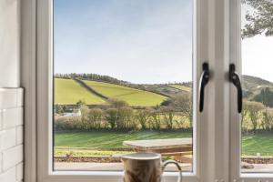 a window with a view of a green field at Longpark Linhay in Paignton