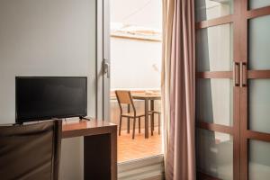 a room with a television and a table with a dining room at Hotel Madanis Liceo in Hospitalet de Llobregat
