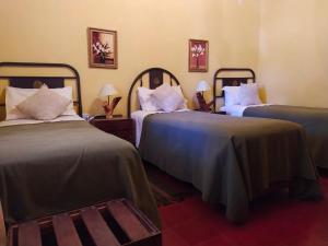 a room with two beds and two tables with lamps at La Sala Hotel Boutique in Tinogasta