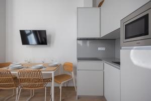 cocina con mesa con sillas y microondas en FLORIT FLATS - The Mediterraneo Apartments, en Valencia