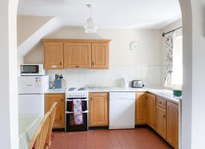 a kitchen with white appliances and wooden cabinets at Inish Holiday Cottage Kilmore by Trident Holiday Homes in Kilmore Quay