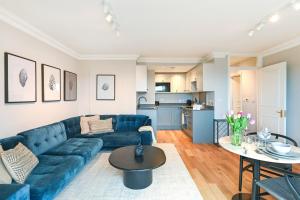 a living room with a blue couch and a table at Buckingham and Lloyds - South Kensington in London