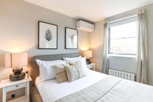 a bedroom with a white bed and a window at Buckingham and Lloyds - South Kensington in London