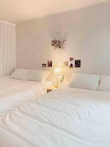 two white beds in a white bedroom with a lamp at Seoul center new Sindang station in Seoul