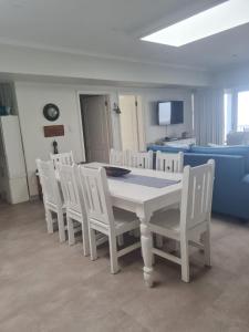 a dining room with a white table and white chairs at Point Village Accommodation - Stephen in Mossel Bay