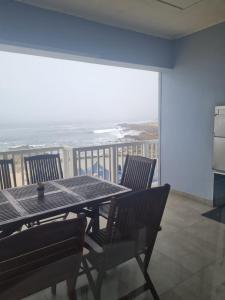 a table and chairs on a balcony with the ocean at Point Village Accommodation - Stephen in Mossel Bay