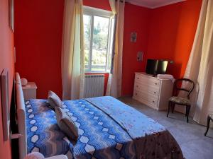 sypialnia z czerwonymi ścianami, łóżkiem i oknem w obiekcie Casavacanze Azzurra w mieście Sarzana