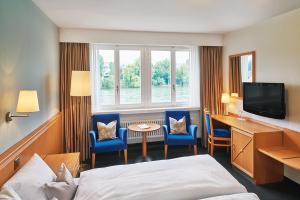 a hotel room with a bed and a desk and a tv at Hotel Schiff am Rhein in Rheinfelden