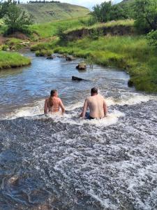 a man and a woman sitting in a river at Tafeni Farm Cottages in Swartberg