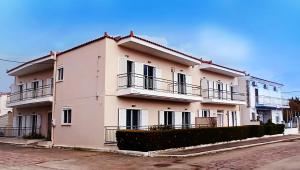 Un grand bâtiment blanc avec balcon se trouve dans une rue. dans l'établissement Arisvi All Seasons Hotel, à Skala Kallonis