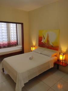 a bedroom with a large white bed with two lamps at Pousada Viva Praia in Paracuru