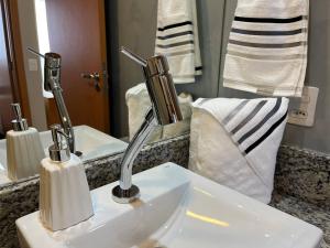 een wastafel in de badkamer met 2 kranen en een spiegel bij Mar & Descanso Itaparica in Vila Velha