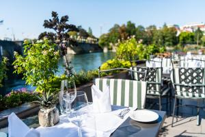uma mesa com copos e pratos numa varanda com um rio em Hotel Schiff am Rhein em Rheinfelden