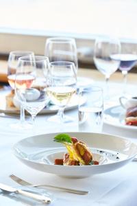 um prato de comida numa mesa com copos de vinho em Hotel Schiff am Rhein em Rheinfelden