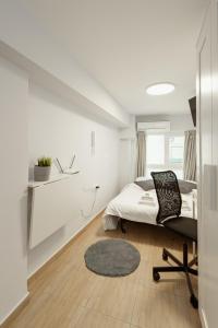 um quarto branco com uma cama e uma cadeira em Downtown Studio Thessaloniki em Tessalônica