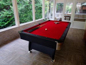 a red pool table in a room with windows at Frank Vendégház in Veszprémvarsány