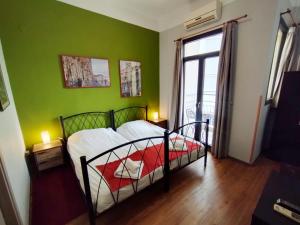 a bedroom with a bed with a green wall at RentRooms Thessaloniki in Thessaloniki