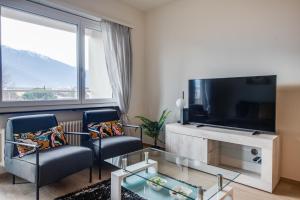 un soggiorno con 2 sedie e una TV a schermo piatto di RELAX Ortensia Apartment a Locarno