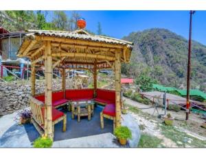 a wooden gazebo with a table and red benches at Aqua Splash Camp, Rishikesh in Rishīkesh