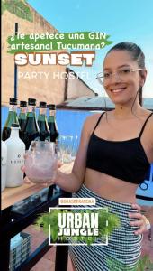 a woman standing in front of a bar holding a drink at Urban Jungle Hostel in San Miguel de Tucumán