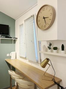 a desk with a clock on a wall next to a window at Charmant studio neuf proche de paris in Bagnolet