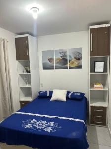 a bedroom with a blue bed and some shelves at Aero-Quarto Aconchegante in Bayeux