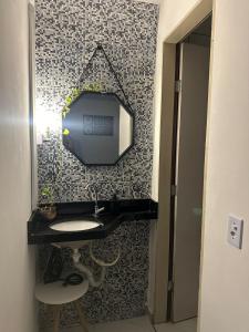 a bathroom with a tv on a wall with a sink at Aero-Quarto Aconchegante in Bayeux