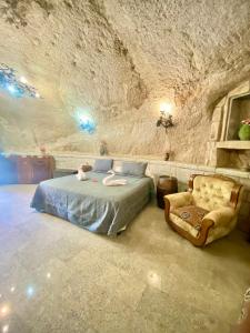 a bedroom with a bed and a chair in a cave at Cueva romántica - Jacuzzi in La Cabrera