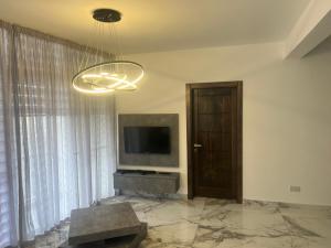 a living room with a television and a chandelier at Maisonette 2 in Munxar