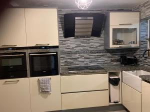uma cozinha com armários brancos e um micro-ondas em 3 bedroom house Colchester em Colchester
