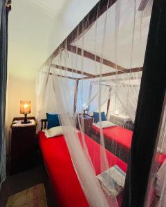 - une chambre avec 2 lits rouges à baldaquin dans l'établissement Swarnapaya résidence, à Bentota