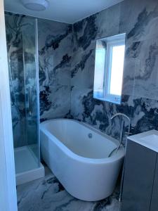 uma banheira branca na casa de banho com uma janela em 3 bedroom house Colchester em Colchester