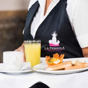 Hotel La Pedregosa في Mérida: نادل مع طبق من الطعام وكأس من عصير البرتقال