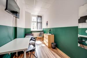 a room with green and white walls and a table and chairs at Hostel Kattowitz in Katowice